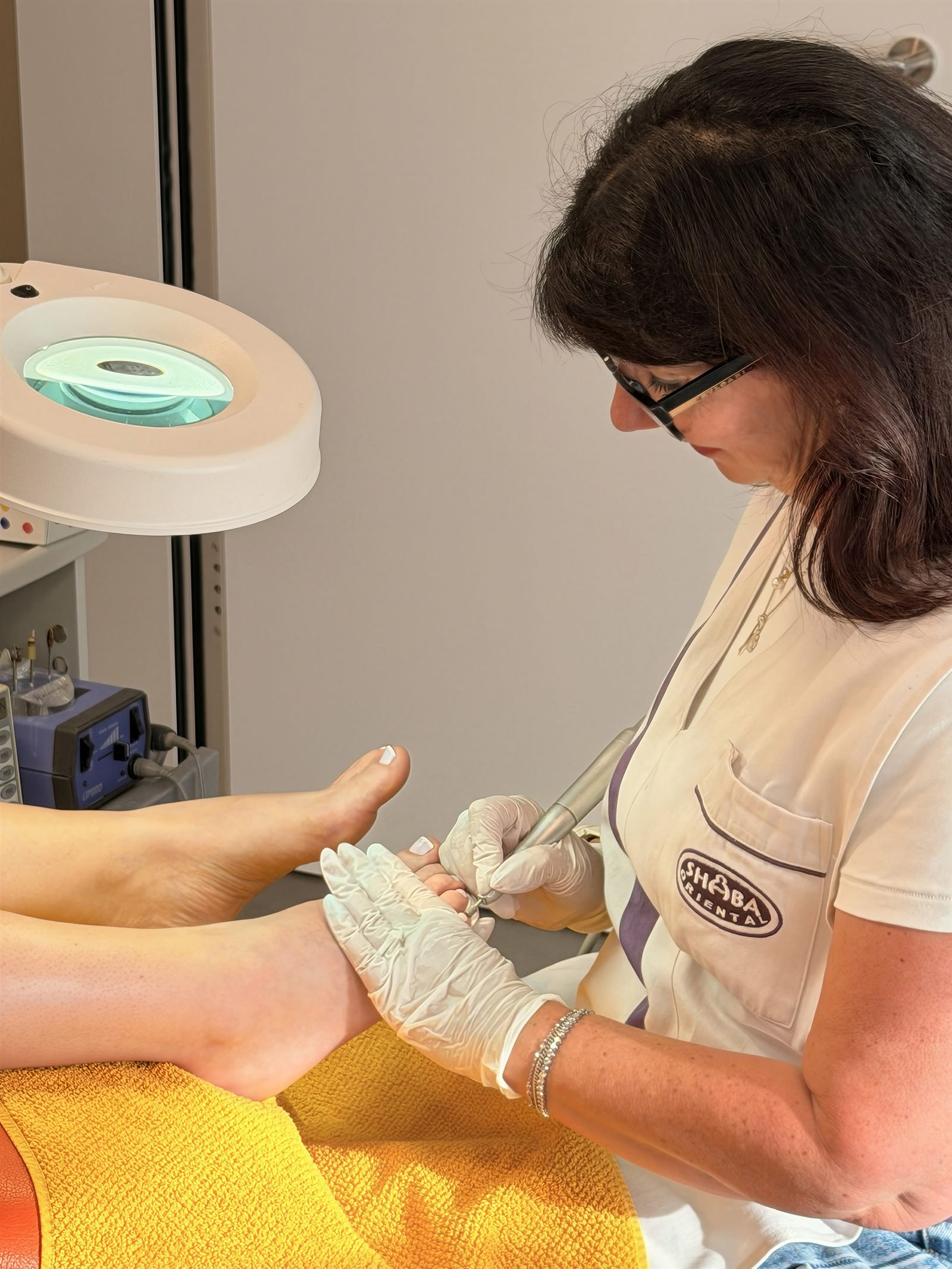 Andrea Schoch bei der medizinischen Fusspflege – mit Handschuhen und Lupenlampe an der Nagelpflege